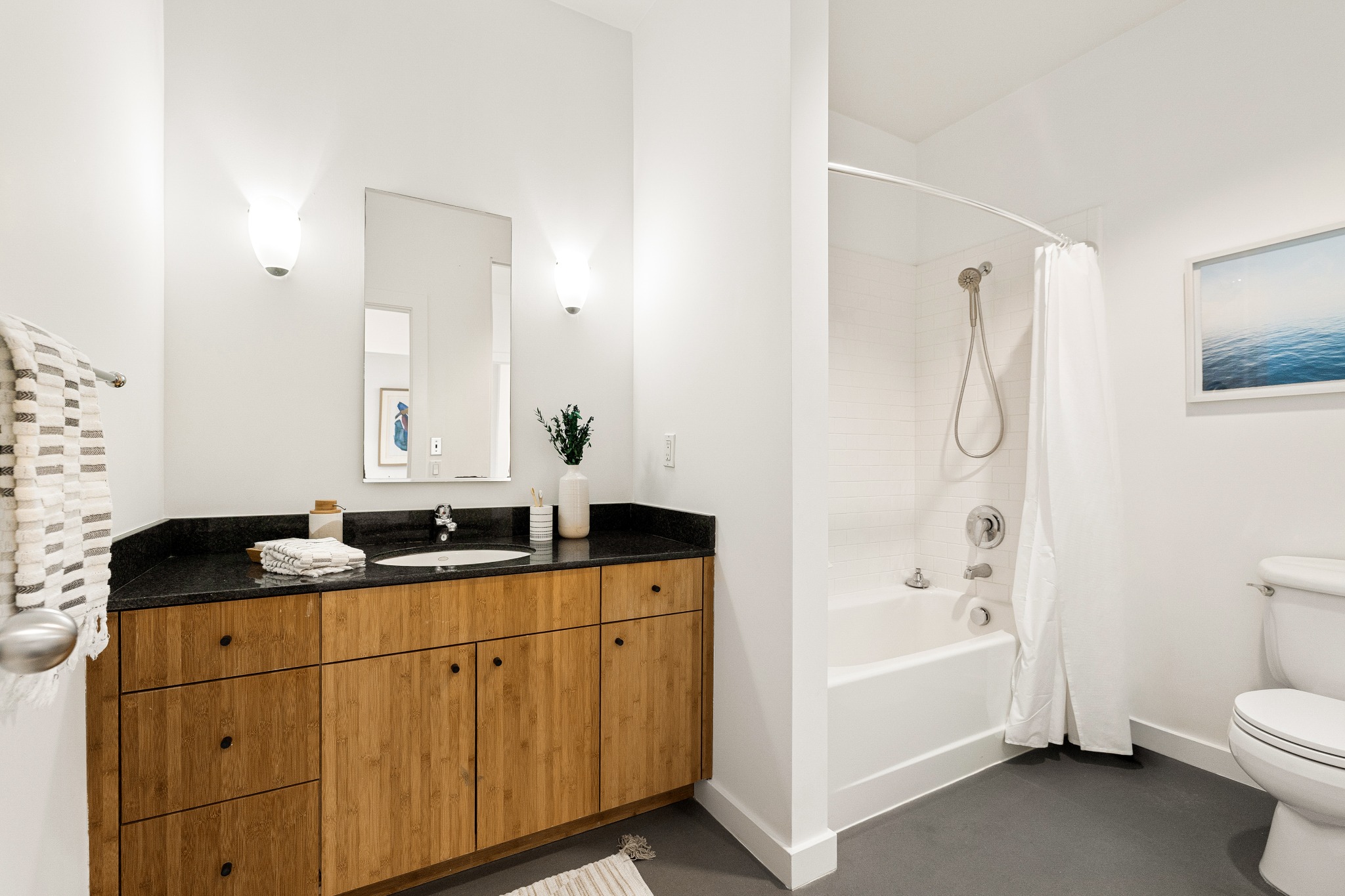 Full bath with wood vanity and black counter
